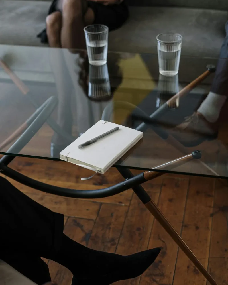 Close-up of a counseling session with two glasses of water and a notepad on a glass table.